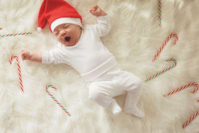baby wearing santa hat in bed of candy canes