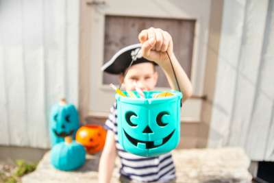 kid holding teal pumpkin filled with allergy free candy