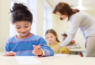 Smiling Little Girl holding Pen and Writing on Paper