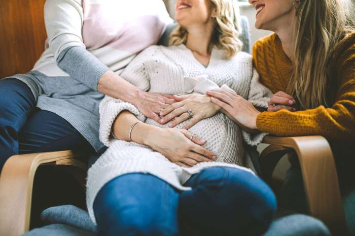 parents and pregnancy surrogate holding pregnant belly