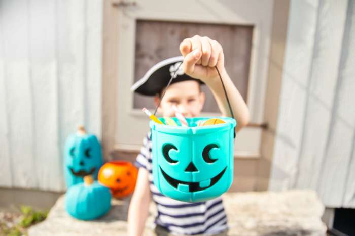 kid holding teal pumpkin filled with allergy free candy