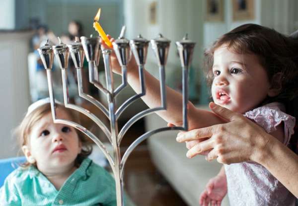 kids lighting Hanukkah menorah