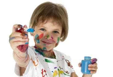 Little girl holding paint brush while covered in paint