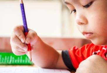 Preschool boy holding red pencil