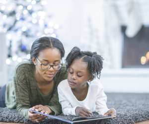 Mom reading kwanzaa book to her daughter