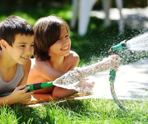 two boys using sprinklers in backyard