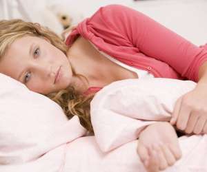 Sad teen girl laying alone on bed